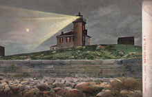 Load image into Gallery viewer, Lighthouse on a hill with a beam of light shining, surrounded by rocks and grass.