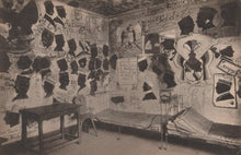 Load image into Gallery viewer, Room with walls covered in posters and notices, featuring a bed and table.