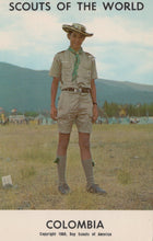 Load image into Gallery viewer, Scout in uniform standing in a field with mountains in the background, labeled 'Scouts of the World, Colombia'.
