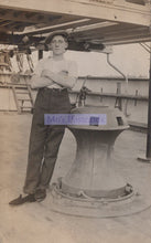 Load image into Gallery viewer, Vintage black and white photo of a man standing on a ship with a large wheel.