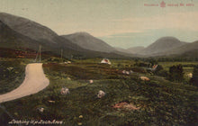 Load image into Gallery viewer, Scenic view of a valley with mountains and a road, featuring sheep and a postcard-like border.