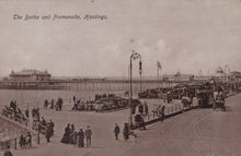 Load image into Gallery viewer, Vintage black and white photo of a promenade with people and vehicles, featuring text 'The Baths and Promenade, Hastings'.