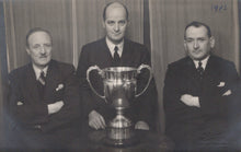 Load image into Gallery viewer, Three men in suits posing with a large trophy in front of a curtain, with '1942' written on it.