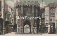 Load image into Gallery viewer, Vintage street scene with a large stone archway and colorful signs