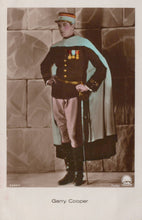 Load image into Gallery viewer, Man in formal military uniform with cape and hat, standing against a stone wall.