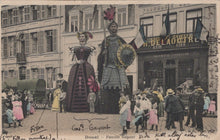 Load image into Gallery viewer, Vintage postcard of giant figures in a street scene with people and buildings.