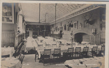 Load image into Gallery viewer, Vintage black and white photo of a dining hall interior with tables, chairs, and decorative elements.