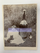 Load image into Gallery viewer, Vintage-style photo of a person sitting outdoors with a large bottle and smaller bottle, overlaid with 'Mo's Postcards' text.