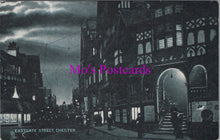 Load image into Gallery viewer, Vintage black and white postcard of Eastgate Street, Chester with a dark sky.
