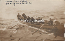 Load image into Gallery viewer, Vintage postcard of a group in a rowboat on water with text &#39;Whaler from Violent picking up a torpedo.&#39;
