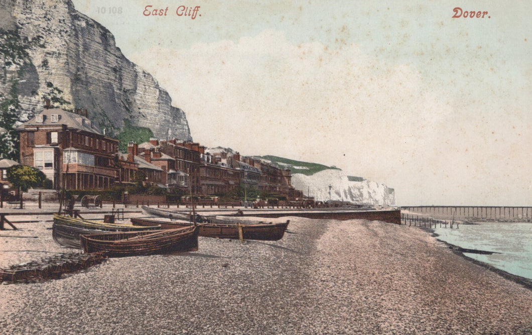 Vintage postcard of East Cliff, Dover with buildings and boats on a pebbly beach.