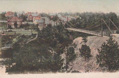 Vintage-style image of a suspension bridge over a landscape with buildings and trees.