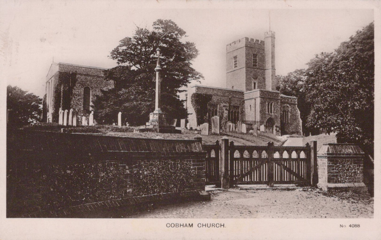 Vintage black and white photograph of a church with a gate and trees in the background