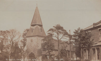 Vintage photograph of a church with a tall spire and surrounding trees.