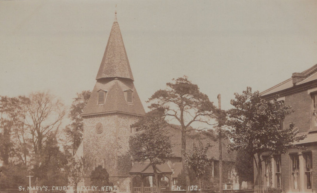Vintage photograph of a church with a tall spire and surrounding trees.