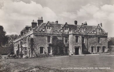 Historic stone building with multiple chimneys under a cloudy sky