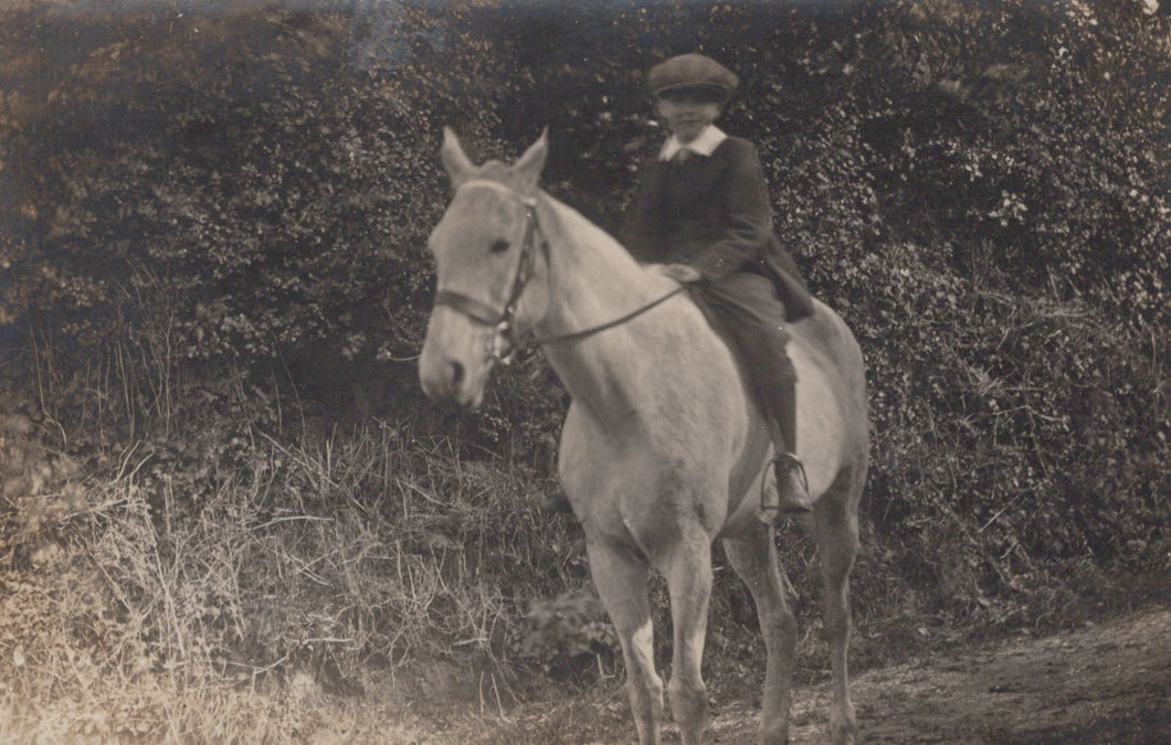 Vintage black and white photo of a child riding a horse in a natural setting