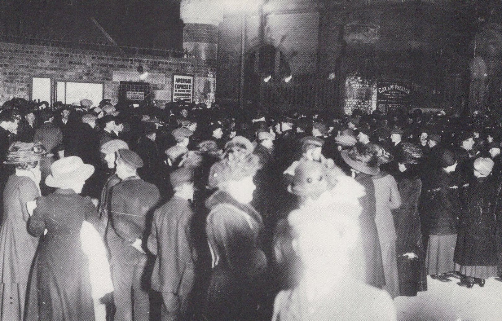 Vintage black and white photograph of a crowded street scene with people in formal attire.