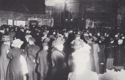 Vintage black and white photograph of a crowded street scene with people in formal attire.
