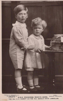 Two young boys standing next to a fishbowl in a vintage black and white photograph.