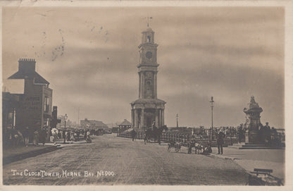 Vintage photograph of a clock tower in Herne Bay, featuring a street scene with people and vehicles.