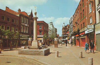 Vintage street scene with a central column and people walking on a sidewalk.