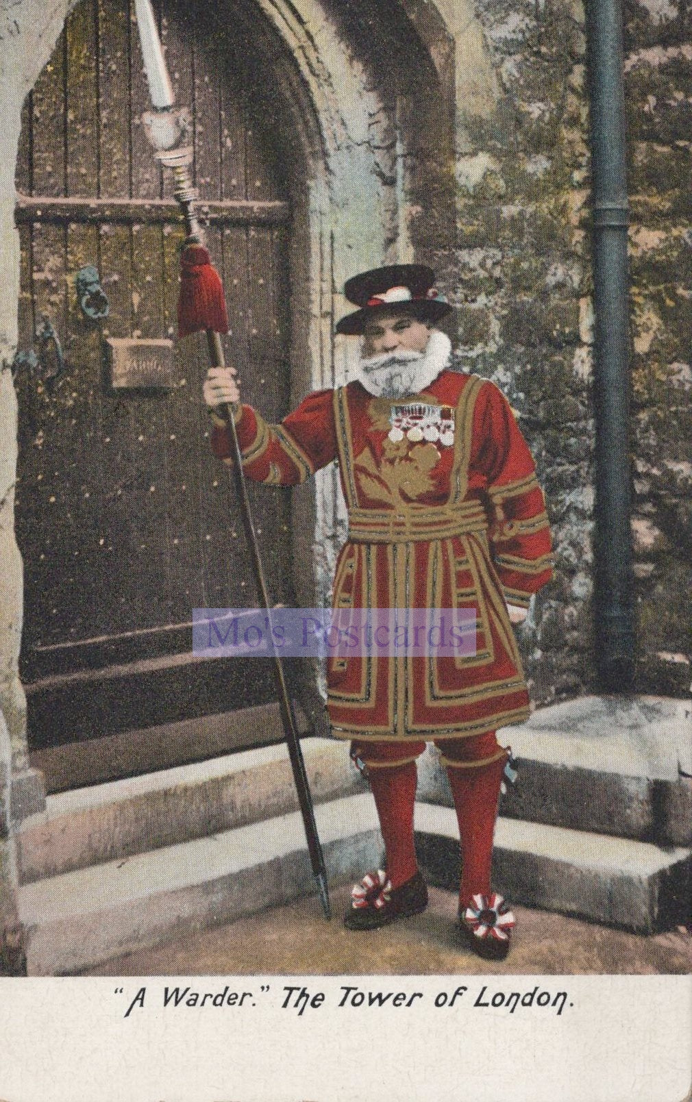 Man in a red and gold costume holding a staff, standing in front of a stone archway.