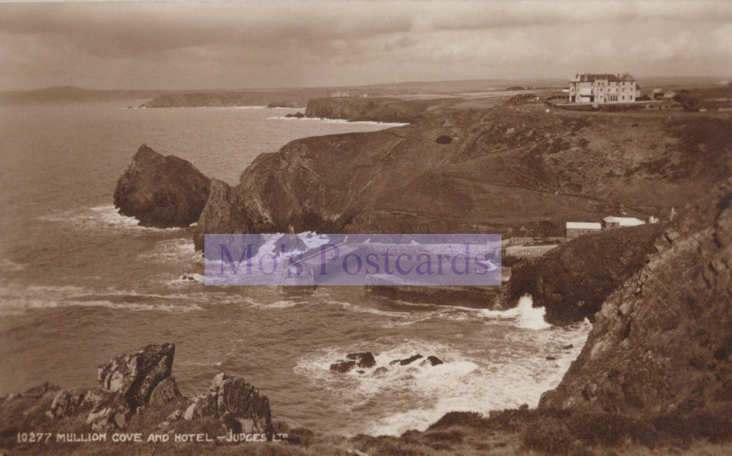 Sepia-toned image of a coastal scene with cliffs and a building.