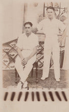 Load image into Gallery viewer, Two men in cricket uniforms standing outdoors with a decorative background
