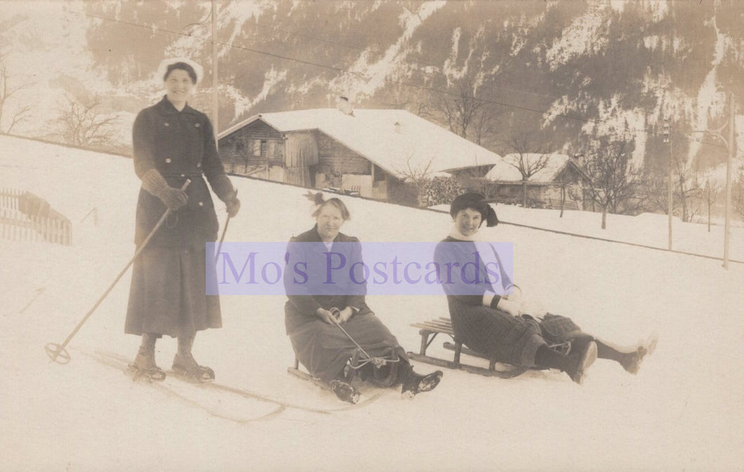 Vintage photograph of people skiing and sledding in a snowy landscape with a building in the background.