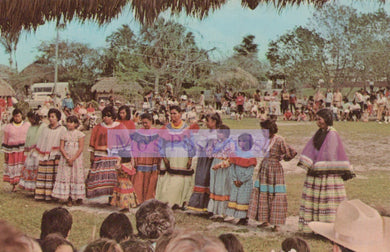 Group of people in traditional clothing holding a colorful banner outdoors.