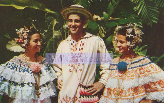Three people in traditional attire standing among tropical plants