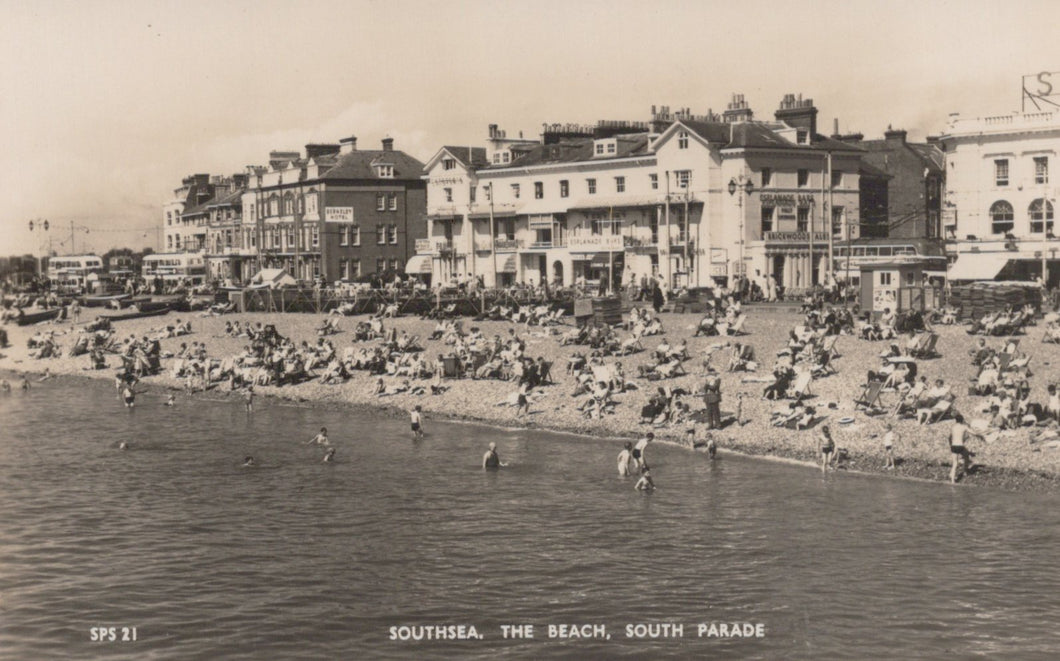 Vintage black and white photo of a beach scene with people and buildings.