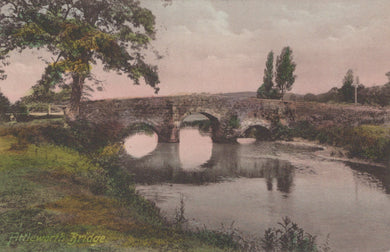 Stone bridge over a calm river with trees and grass on either side, vintage coloration.