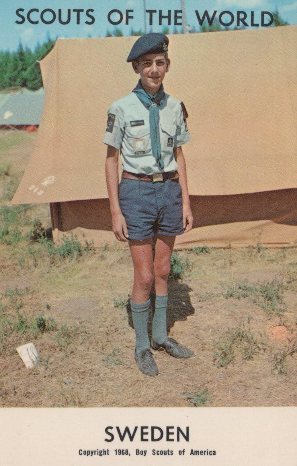 Scout in uniform standing in front of a tent with 'Scouts of the World' and 'Sweden' text.
