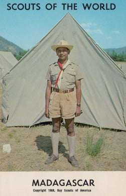 Scout in uniform standing in front of a tent with 'Scouts of the World' and 'Madagascar' text.
