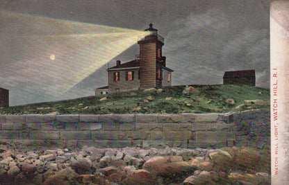 Lighthouse on a hill with a beam of light shining, surrounded by rocks and grass.