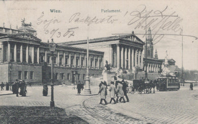 Vintage black and white photo of a city street with people and horse-drawn carriages, featuring architectural buildings.