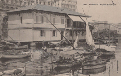 Vintage black and white photo of a waterfront scene with boats and a building in Algèr.