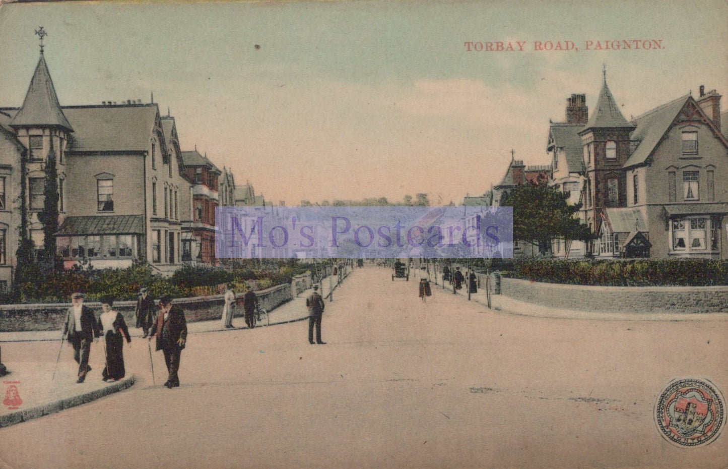 Vintage postcard of a street scene with people and buildings in Paignton, featuring 'Mo's Postcards' watermark.