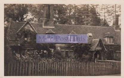 Vintage black and white photograph of a house with a picket fence and trees.
