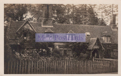 Vintage black and white photograph of a house with a picket fence and trees.