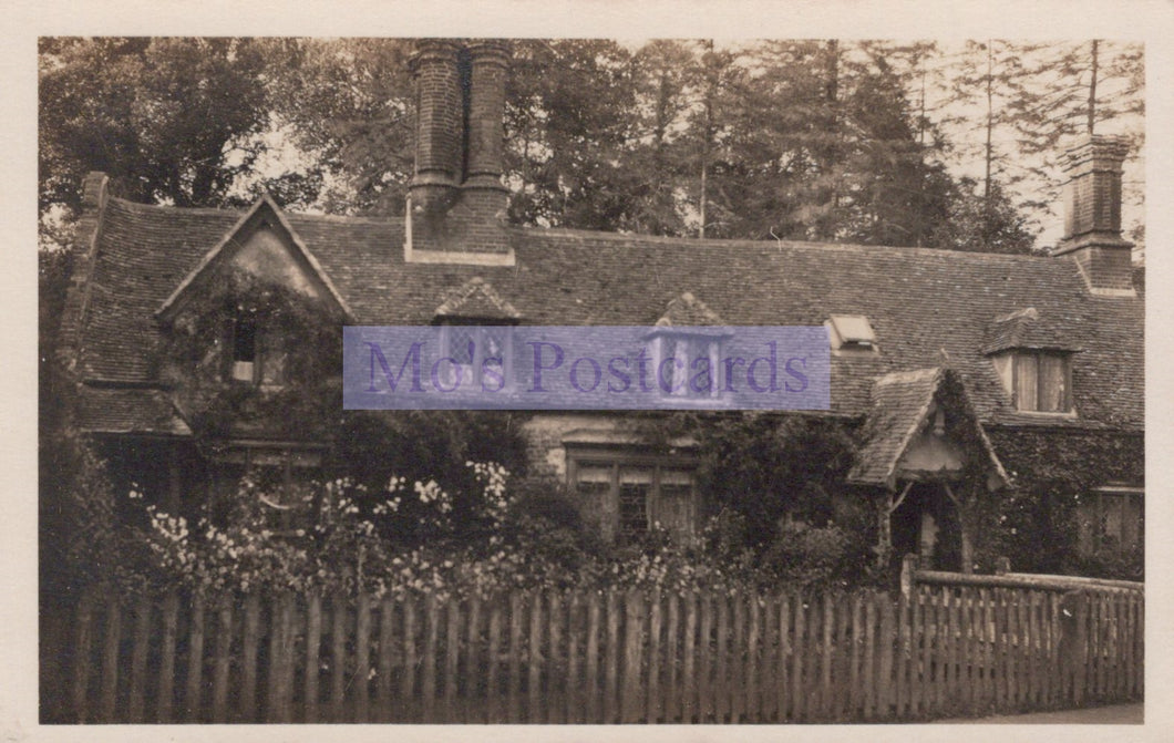 Vintage black and white photograph of a house with a picket fence and trees.