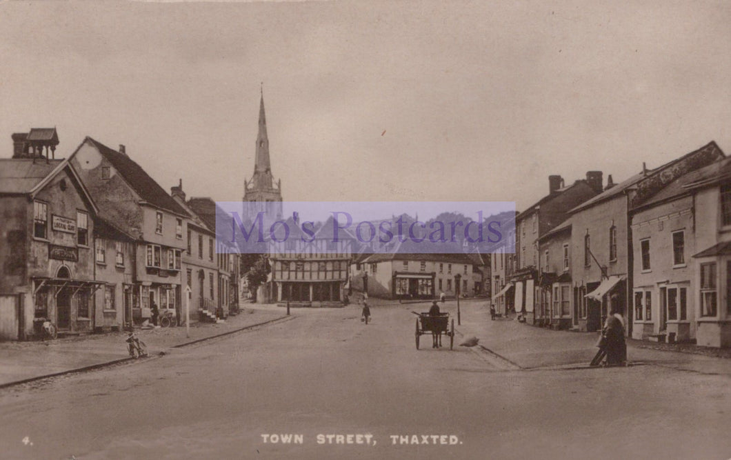 Vintage black and white photograph of a town street with buildings and a church spire.