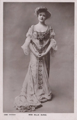 Vintage black and white photograph of a woman in an ornate dress against a plain background