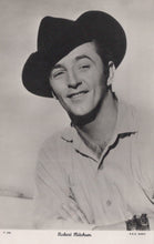 Load image into Gallery viewer, Black and white portrait of a man wearing a cowboy hat and shirt, with a camera around his neck.

