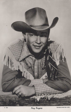 Vintage black and white photo of a person in cowboy attire with a large hat and fringed shirt.