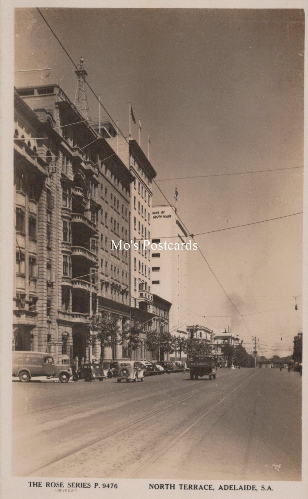 Vintage black and white photo of a city street with buildings and car 