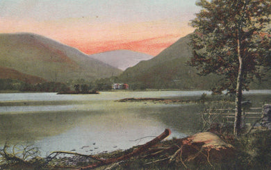 Landscape with a lake, mountains, and a cabin at sunset.