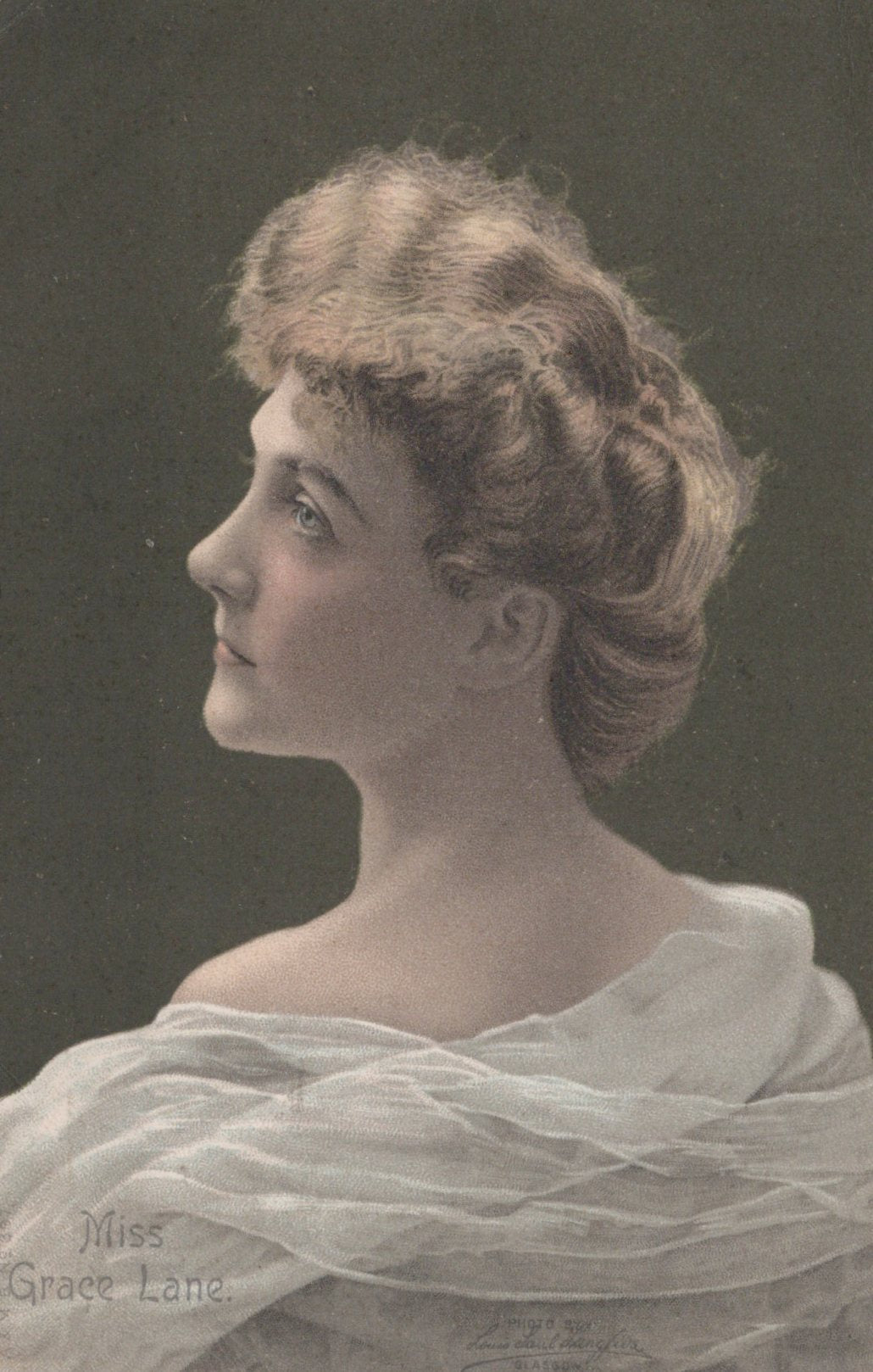 Vintage portrait of a woman with styled hair and a light shawl against a dark background.